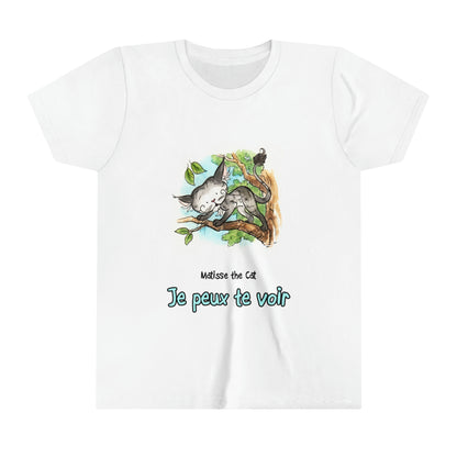 A white official, Matisse the Cat children’s t-shirt with the slogan ‘'Je peux te voir' (I can see you) showcases Matisse perched on a tree branch, gazing downward with a curious expression, capturing the playful and inquisitive nature of the character.