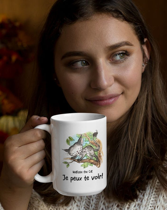 Matisse the cat je peux te voir 15oz jumbo mug held by a young woman looking thoughtful.