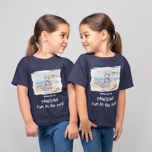 A navy blue official, Matisse the Cat children’s t-shirt with the slogan ‘Pawsome Fun in the Sun ‘ showcases Matisse at the beach, relaxing on a sun lounger sipping a mile shake. Worn by twin girls, standing side by side looking at each other.