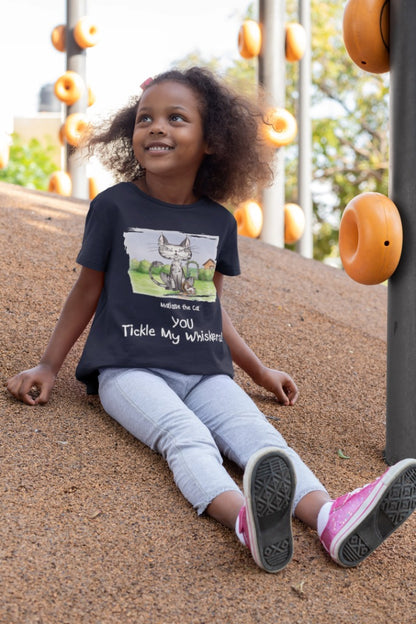 A navy blue official, Matisse the Cat children’s t-shirt with the slogan ‘YOU Tickle My Whiskers ‘ showcases Matisse sitting in his garden smiling with a sleeping hedgehog curled up beside him resting on his leg. Worn by a young girl sitting on a hill in a play park.