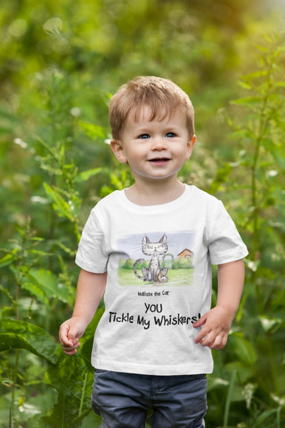 A white official, Matisse the Cat children’s t-shirt with the slogan ‘YOU Tickle My Whiskers ‘ showcases Matisse sitting in his garden smiling with a sleeping hedgehog curled up beside him resting on his leg. Worn by a young boy walking through foliage.