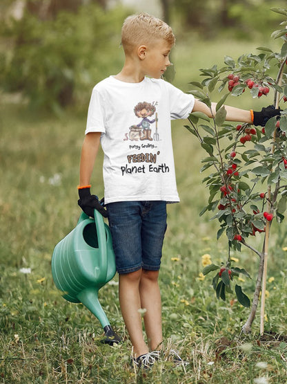 A white official Grolings kids' t-shirt, featuring the phrase 'Pongy Groling... Feedin’ Planet Earth.' The t-shirt showcases Pongy Groling, a character from ‘Matisse and the Topsy-Turvy Farm,’ standing beside a sack of compost. Pongy Groling is holding a garden fork, and a friendly worm is watching. Worn by a young boy standing beside a recently planted tree holding a watering can. 